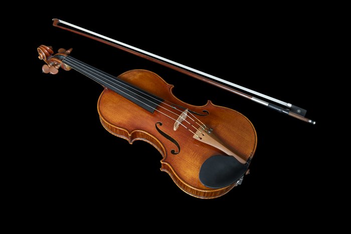 Violine mit Bogen vor schwarzem Hintergrund.