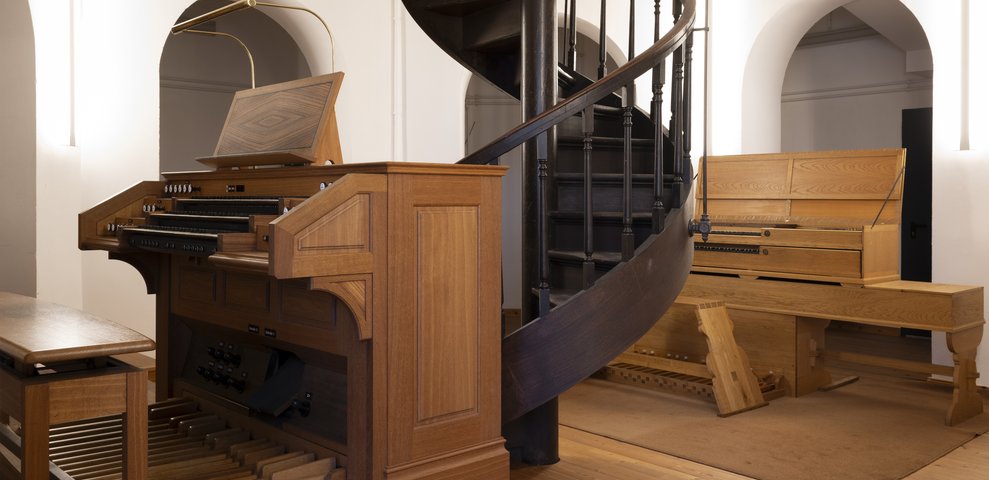 Interior view of the music department at HfK Bremen, featuring wooden organs and a spiral staircase on Dechanatstraße.