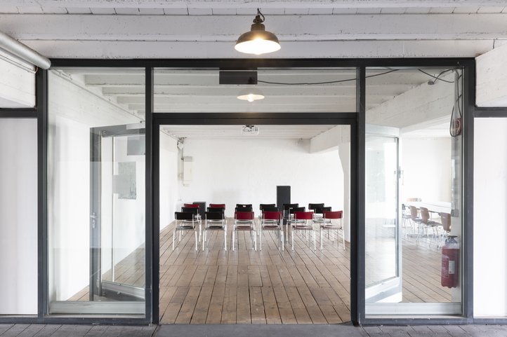 Conference room with chairs, wooden floor, and large glass windows.