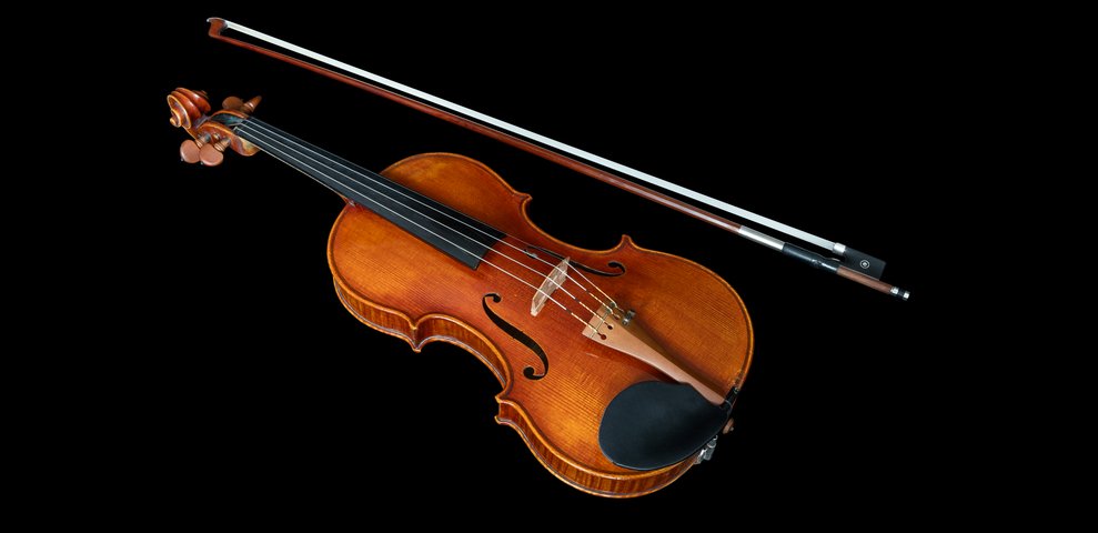 Violin with bow against black background.