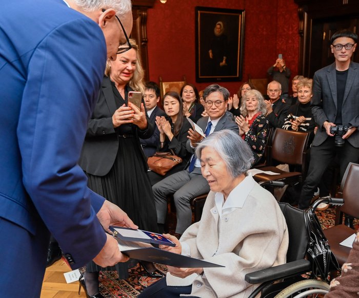 Mayor Andreas Bovenschulte presents Professor Younghi Pagh-Paan with the Order of Merit of the Federal Republic of Germany in the fireplace room of Bremen City Hall.