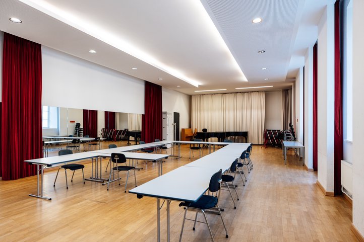 HfK Bremen chamber music hall, bright, spacious room with red curtains and U-shaped tables.