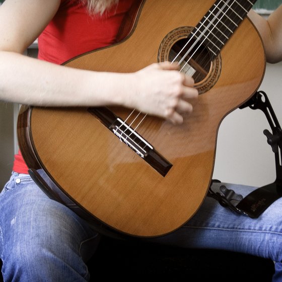 Nahaufnahme einer Person, die eine klassische Gitarre spielt, mit Fokus auf das Instrument und die Hand des Spielers.